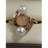 A gold colour metal ring set with two pearls and a cat's eye. Size R. provenance 80 rose Street