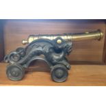 A Desk Top Miniature Brass Canon. On a cast iron carriage.