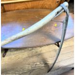 An antique Scythe. With long handle and curved steel blade.