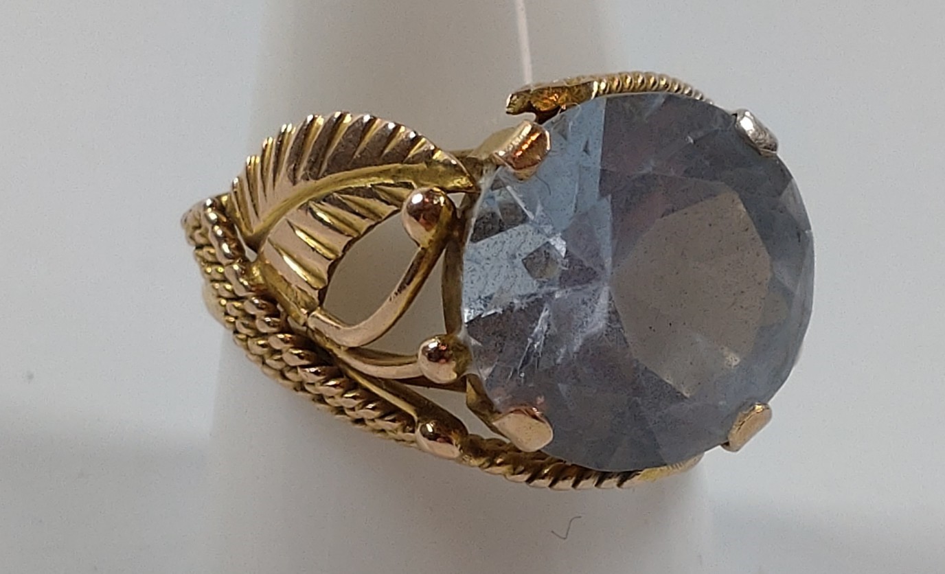 A gold colour metal ring set with a blue stone. Size S. provenance 80 Rose Street Wokingham.