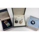 A collection of four silver necklaces with various decorative pendants, all boxed.