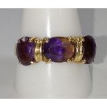 A gold colour metal ring set with three possible amethyst size K. provenance 80 Rose Street