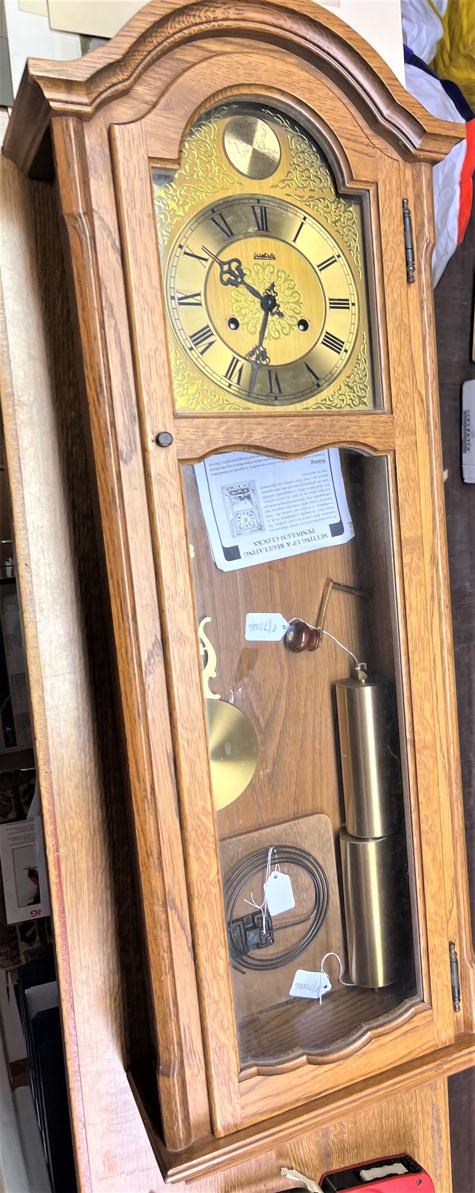 A Good Oak Cased Chiming Wall Clock. Circa 1970. Complete with grid iron pendulum, two brass weights