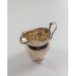 A silver cream jug with beaded decoration (some dents to the body). Marks rubbed.