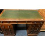 A mahogany pedestal desk the green tooled leather top with nine drawers about the knee, on plinth
