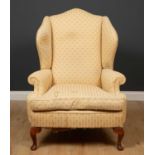A Brights of Nettlebed wingback armchair, with cream floral upholstery on pad feet, Brights of