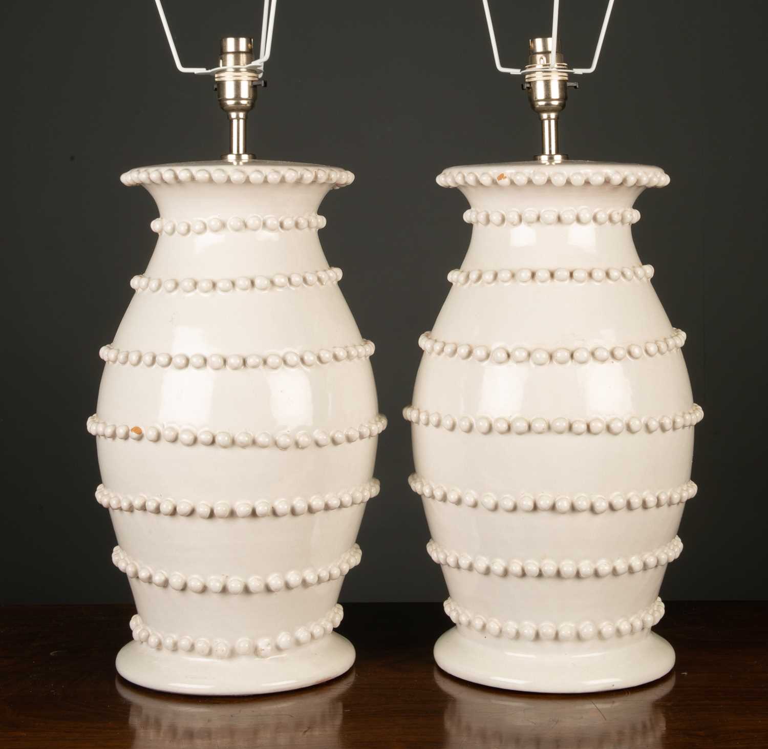 A pair of white glazed pottery lamps of baluster form with applied decoration, each 46cm high