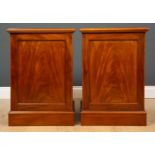 A pair of Victorian mahogany bedside cabinets each with panelled doors and a single drawers,