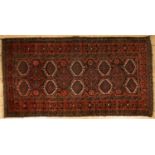 An Baluch blue and red ground rug with central pairs of medallions within a banded border, 190cm x