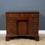 A George III mahogany and stainwood inlaid kneehole desk with seven drawers, brass swan neck