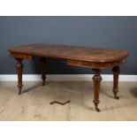 A Victorian burr walnut extending wind out dining table with turned tapering legs and brass casters,