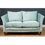 A modern blue upholstered two-seater sofa, the velvet feel upholstery on wooden turned castors,