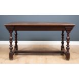 An antique oak centre table the plank top with cleated ends and moulded frieze, on turned legs