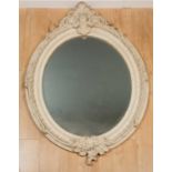 A large oval mirror with bevelled mirror plate within a resin scrolling foliate border and cartouche