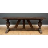 An 18th century oak refectory table the plank top on intricately carved urn shaped trestle base,