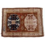 An antique Oriental brown ground rug with two central stylised motifs within a triple banded border,
