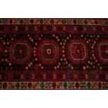 A modern machine made red ground rug, with six central medallions surrounded by bands of decoration,