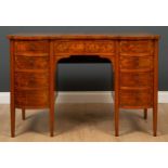 An Edwardian serpentine fronted kneehole desk with inlaid decoration and nine drawers around the