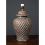A pottery table lamp with twisted decoration to the body and gilt painted, formed as a lidded urn,