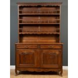 A Continental oak dresser with plate rack above, drawers and cupboards below and panelled sides,