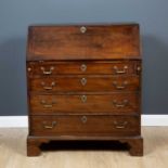A George III mahogany bureau the fall front opening to reveal drawers and pigeon holes above four
