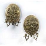 Pair of oval two branch brass wall sconces each embossed with a romantic scene, 28cm x 21cm