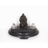 A 19th century bronze figure of a seated scholar, mounted as an inkstand with dished black slate