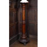 A 19th century turned mahogany torchere of column form with carved paw feet, 135cm high, the top