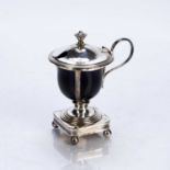 Arts and Crafts style silver mustard pot, with blue glass liner, standing on four bun feet,