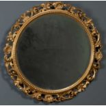 An antique carved giltwood circular mirror frame of scrolling acanthus leaf and scallop shell