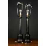 A pair of modern black painted metal table lamps of column form, each with brass paw feet, 55cm