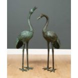 A pair of modern bronze storks one with its head raised, both possibly for use as fountains, the