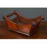 A 19th century mahogany cheese coaster with scrolling ends united by turned handles, all standing on