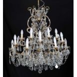 A large cut glass and brassed metal chandelier with two layers of lights, set within extensive