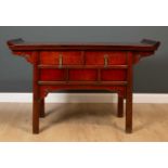 A Chinese elm altar table with scrolling end supports and two drawers with brass fittings, all on