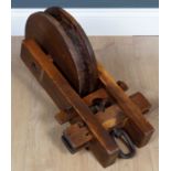 An antique oriental elm and iron pulley the pulley wheel 33cm diameter, the pulley overall 57cm