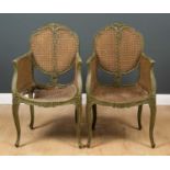 A pair of French green painted caned armchairs with carved flower ornament and reeded cabriole