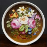 A 19th century circular porcelain plaque decorated with a spray of flowers, the dished plaque