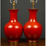 A pair of red glazed pottery vases of baluster form converted to lamps, each 38cm in height