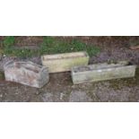 A group of three cast reconstituted stone troughs one with carved rose decoration to the ends,