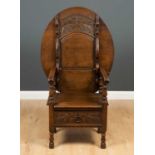 An 18th century style oak monks bench with a folding oval top, a single drawer with carved