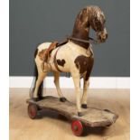A Victorian pull along toy horse, the hessian backed brown and white cow hide on wooden frame with