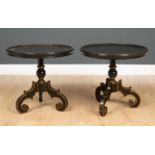 A pair of ebonised and gilt decorated lamp tables with circular dish tops on scrolling feet with