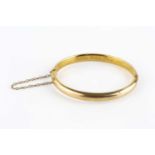 A late Victorian gold bangle, of hinged oval hollow form, the interior inscribed 'Scilly Isles, Xmas