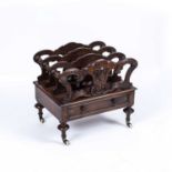 A Victorian walnut canterbury with foliate scroll carved and slatted divisions, base drawer,