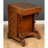An early Victorian walnut Davenport, the leather inset top opening to reveal a satinwood interior