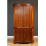 A George III mahogany and satinwood inlaid bow fronted floor standing corner cupboard with tambour