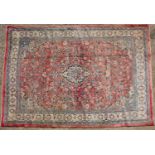 A mid to late 20th century Middle Eastern red ground woollen carpet with a banded border, central