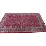 A large Middle Eastern red ground woollen carpet with a banded border and foliate decoration,