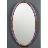 A late 19th / early 20th century gilded and painted oval wall mirror with bevelled glass and an